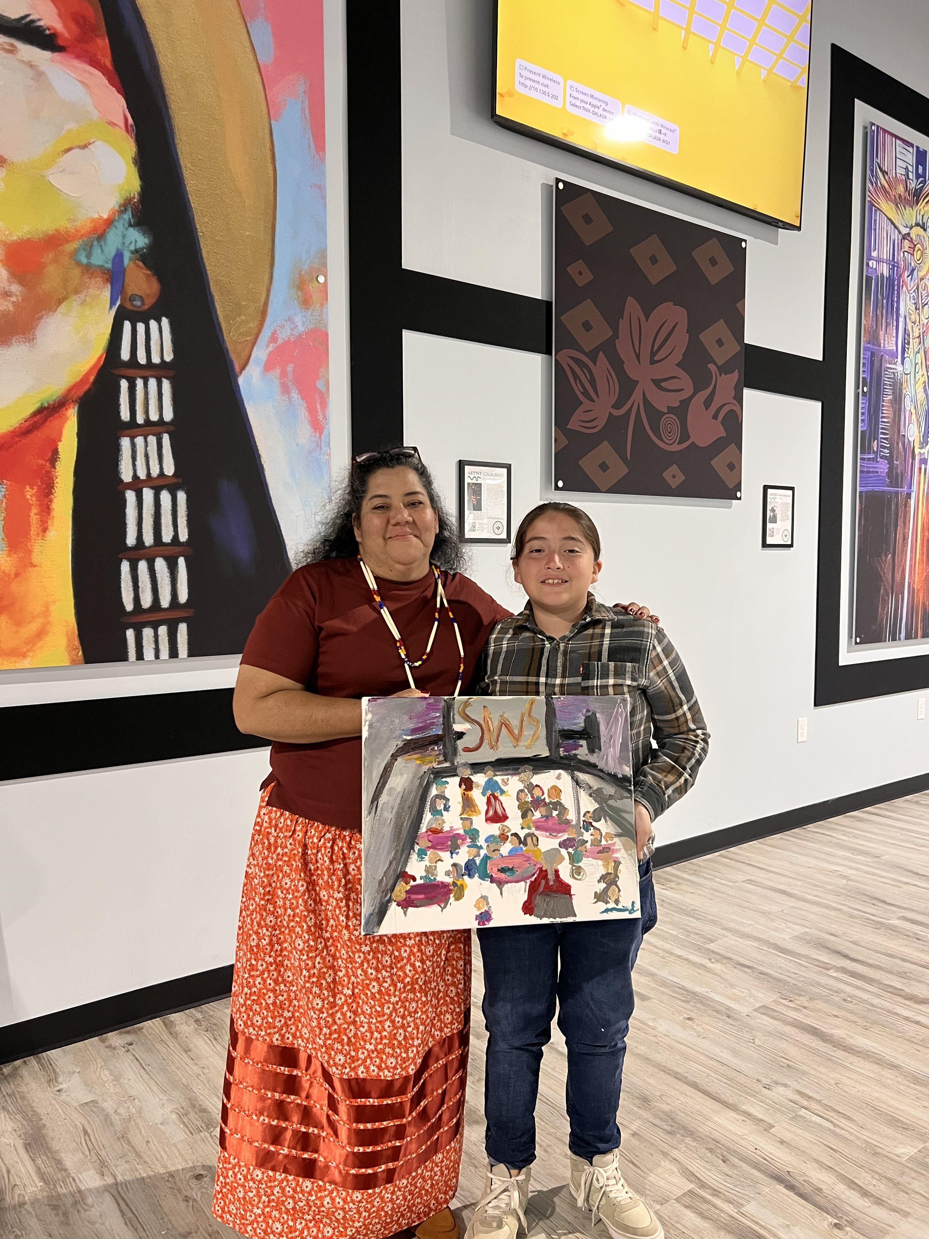Indigenous youth presenting a painting of elders.
